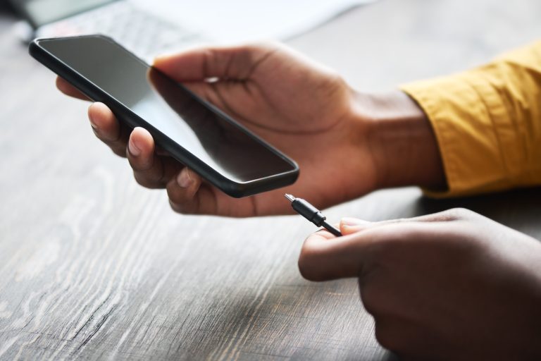 Hands of young African American businessman putting USB in charging connector