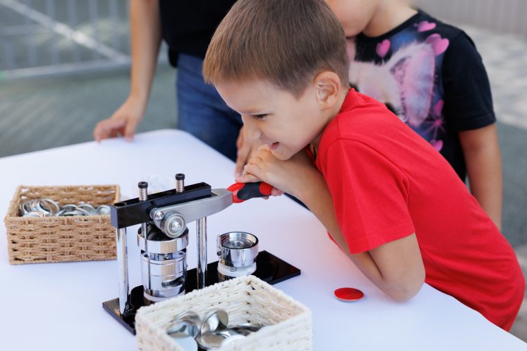 Mechanical manual press. The boy makes a badge.